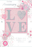 This anniversary card is portrayed as a gentle ode to enduring romance, its look perfectly suited to a quiet celebration in a Canonbury flat overlooking leafy streets. The central element is the word LOVE, each letter raised from the surface and coated in soft, shimmering glitter. The texture invites touch, giving the impression of something carefully crafted rather than mass produced. The O is transformed into a silver-toned heart, slightly more textured than the other letters, providing a focal point that glows against the pale, rosy backdrop. Around this centrepiece, a cloud of delicate blossoms unfolds, rendered in blush pinks, mauves, and soft whites, with subtle grey and silver detailing. The flowers and their trailing vines have a flowing, almost watercolour quality, like ink washed gently across the page, evoking the grace of an English spring garden tucked behind Canonbury's terraces. Tiny decorative touches-scattered petals, curling swirls, and light, wing-like shapes hinting at butterflies-add movement without cluttering the design. The palette of pastel pinks and silvery greys creates a feeling of treasured intimacy, as though the card itself is a keepsake meant to be tucked away and re-read over the years. Elegant script announces On Our Anniversary and I love you today and always, the thin, fluid strokes echoing the curves of the vines that surround the words. Soft lighting enhances the interplay between matte paper, raised glitter, and subtle metallic accents. Overall, the card feels like a quiet, deeply felt expression of love: a paper memento that mirrors the calm, steady warmth of a long-term partnership shared in this peaceful part of North London.